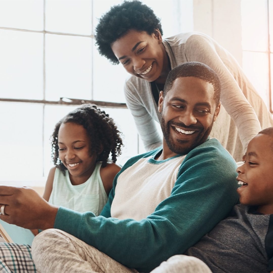 Reading, happy and black family with book on sofa for bonding together on fathers day at home