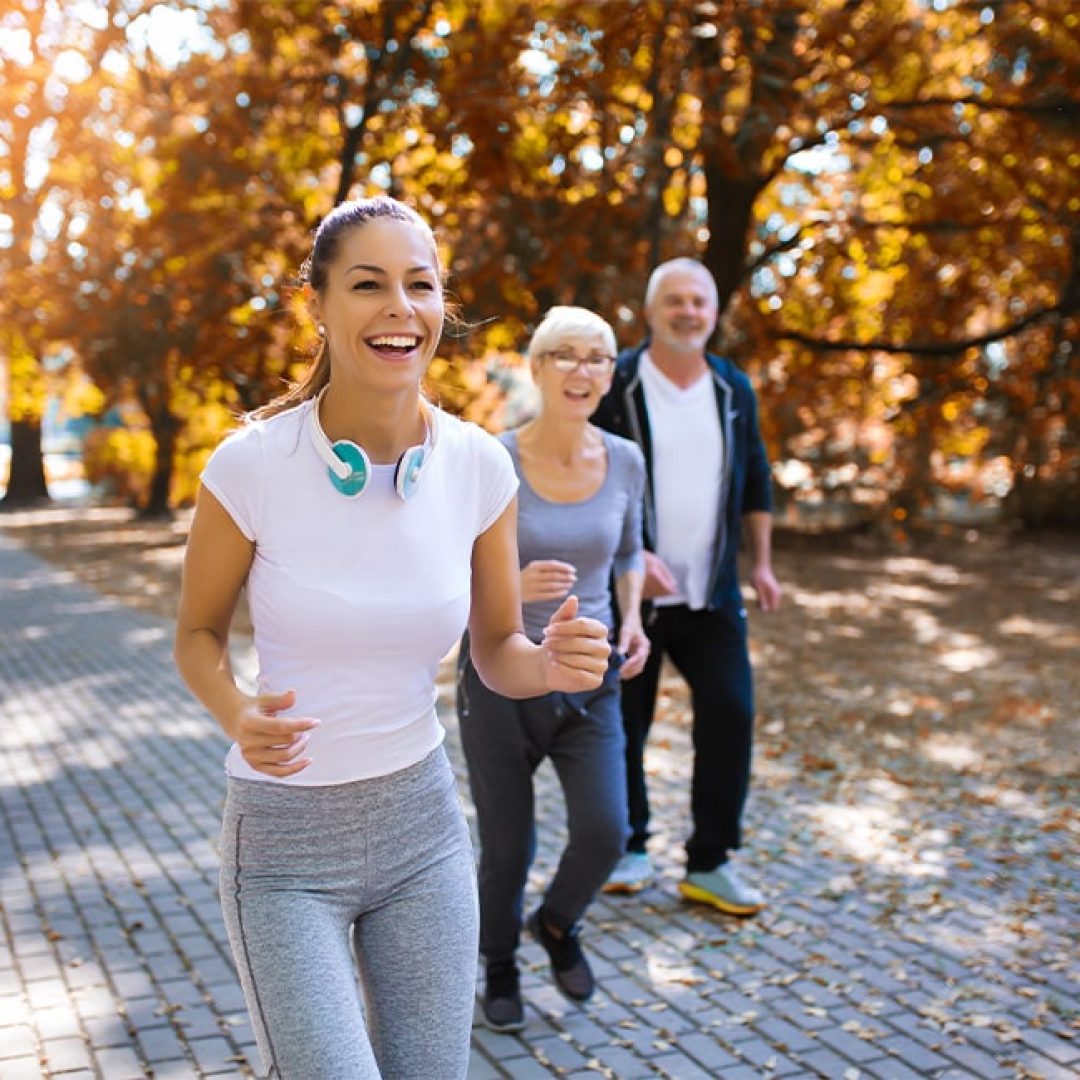 Senior man and woman and young female instructor workout on fresh air.